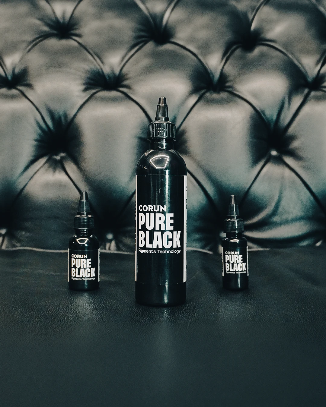 Três frascos reais da linha Pure Black sobre uma poltrona de couro